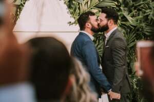 men-wearing-suit-kissing-in-front-of-people-3491999-2